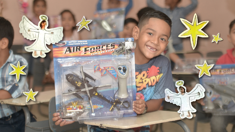Smilling boy holds up toy helicopter in package with star and angel graphic elements